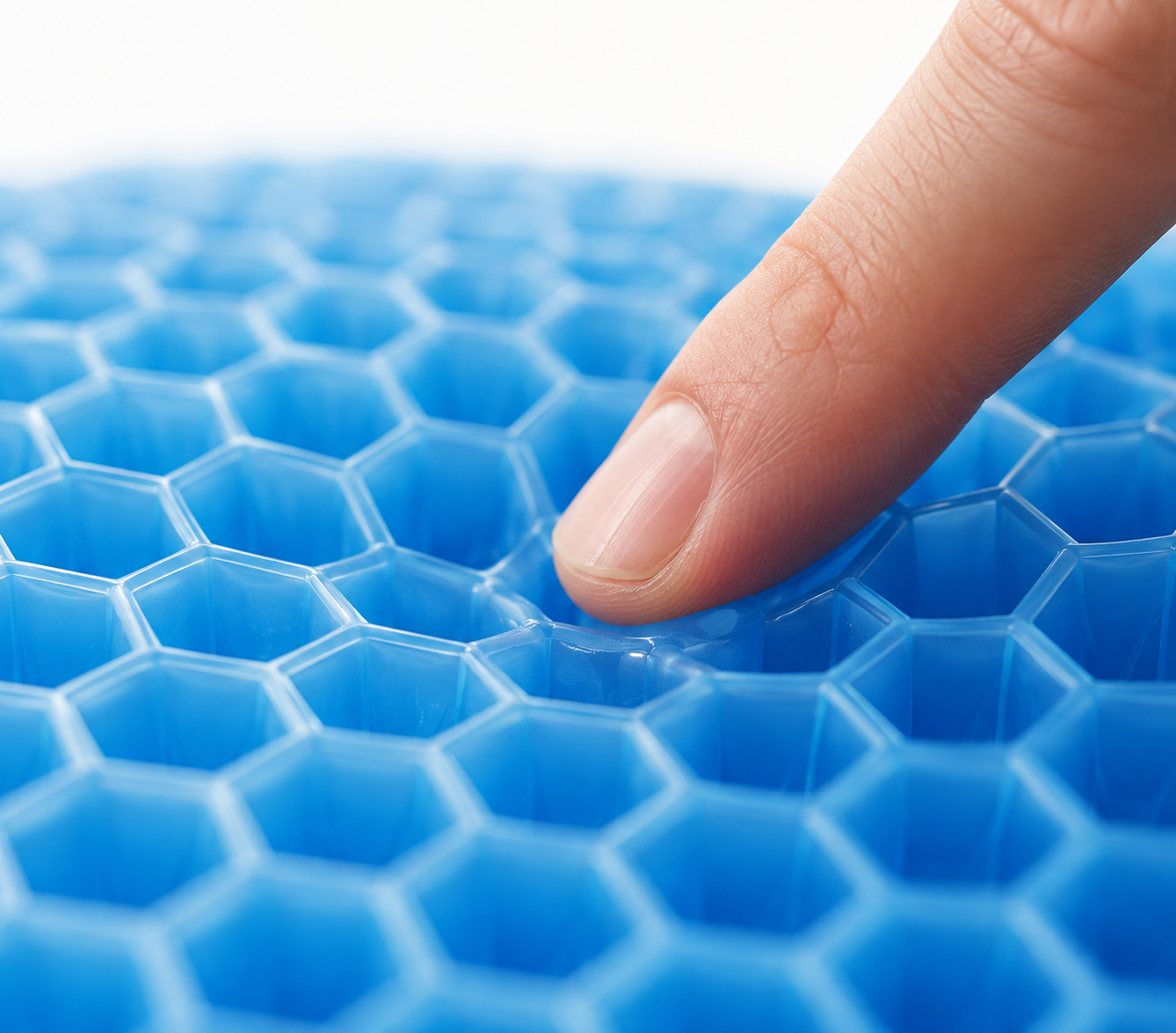 Gros plan sur les alvéoles en gel souple du coussin Corélia, doigt pressant la structure nid d'abeille